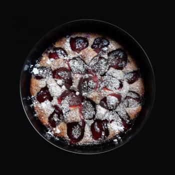 Whole plum pie on black background. Isolated with clipping path.