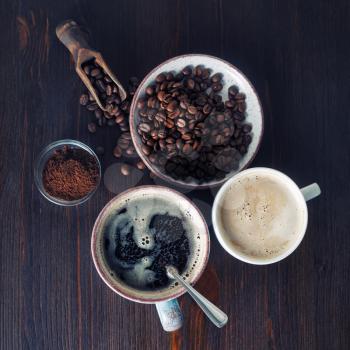 Cups of coffee, coffee beans and ground powder on old wooden background. Top view. Flat lay.