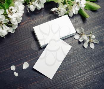 Blank white business cards and flowers on wood table background. Mockup for branding identity.