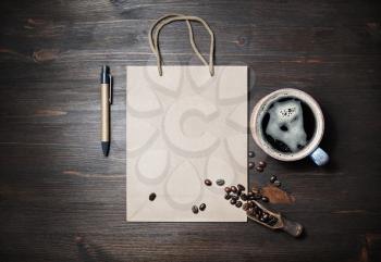 Blank kraft paper bag, coffee cup, coffee beans and pen on wooden background. Space for text. Flat lay.