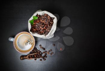 Coffee cup and coffee beans on black wood table background. Copy space for your text. Flat lay.