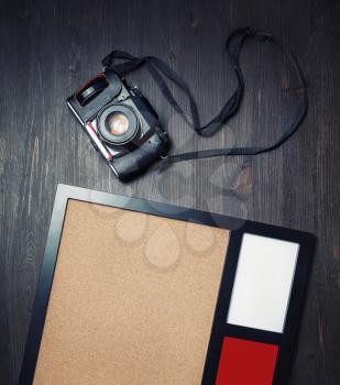 Retro camera and blank photo frame on vintage wood table background. Top view. Flat lay.