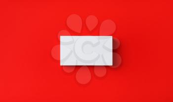 Photo of blank business card on red paper background. Template for branding identity. Mockup for ID. Flat lay.