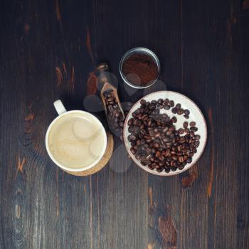 Still life with coffee. Coffee cup, coffee beans and ground powder on wood table background. Flat lay.