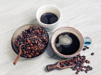 Photo of fresh tasty coffee on light wood table background. Coffee cups and coffee beans.