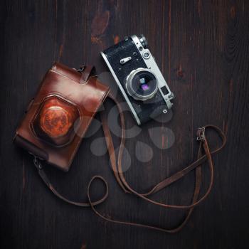 Vintage photo camera and holster on wooden background. Top view. Flat lay.