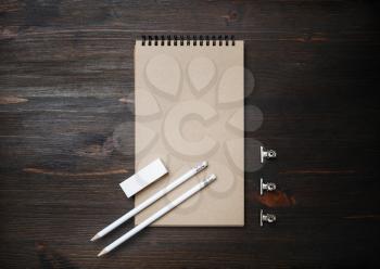 Blank black kraft notebook, pencil and eraser on wooden background. Top view. Flat lay.