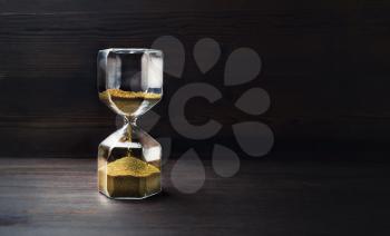 Hourglass on wooden background with copy space. Time Running Out.
