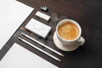 Photo of coffee cup and blank stationery set on wooden background.