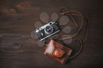 Retro photo camera and holster on wood table background. Flat lay.