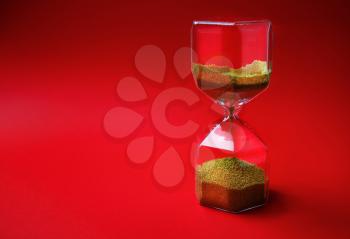 Hourglass on red background with copy space. Time concept.
