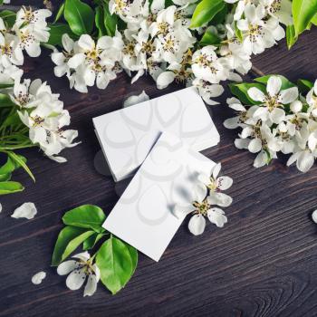 Blank white business cards and flowers on wood table background. Copy space for text.
