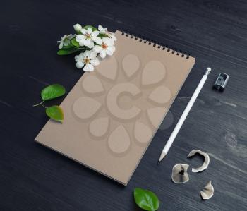 Photo of blank kraft paper notebook, pencil, sharpener and spring flowers on wood table background. Copy space for your text.