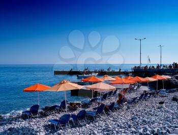 Horizontal vivid stony beach with umbrellas background