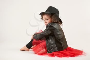 Little girl with black hat sitting and pouting