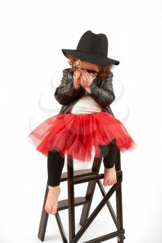 Little girl with black hat sitting on a high stool and shy