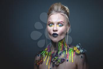 Emotional portrait of a young girl with creative makeup and colorful butterflies on her shoulders
