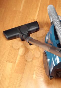 Blue vacuum cleaner  on a oak parquet