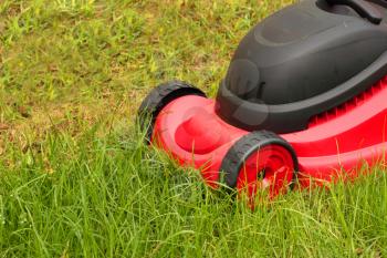 Closeup of  red lawnmower mowing the grass