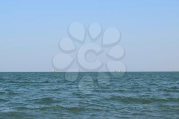Seascape and two ships on the horizon. Sea day and small waves.