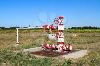 Oil well. The equipment and technologies on oil fields. Oil well in the field, painted in white and red. Oil with modern equipment.