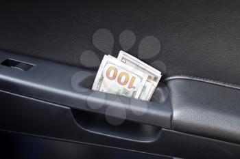 Several notes of US dollars and are folded in half in the door handle of the car. The money in the car.