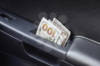 Several notes of US dollars and are folded in half in the door handle of the car. The money in the car.