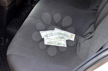 Several banknotes American dollars lie on the car seat. The money in the car.