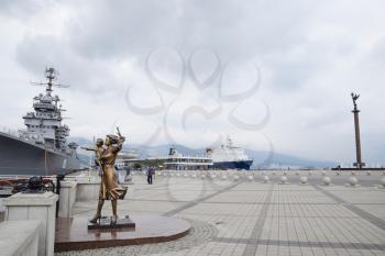 Novorossiysk, Russia - May 28, 2016: Monument to sailor's wife. Warship Admiral Kutuzov. The area of Novorossiysk Sea Commercial Port.