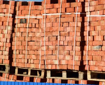 Red bricks stacked into cubes. Warehouse bricks. Storage brickworks products.