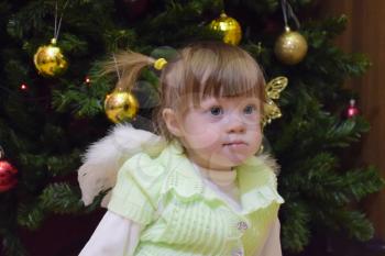 One year old baby girl sitting on the background of the Christmas tree. A child with gray eyes and blond hair.