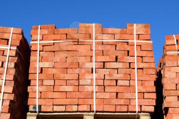 Red bricks stacked into cubes. Warehouse bricks. Storage brickworks products.
