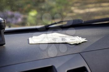 Dollars on a car dashboard under the windshield. American Money.