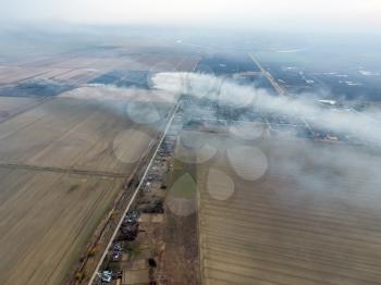 Top view of the small village. Smoke from the burning of straw is spread over the village