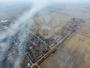 Top view of the small village. Smoke from the burning of straw is spread over the village