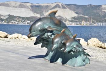 The bronze sculpture of three dolphins on the beach.
