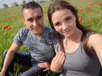 A girl and a guy are sitting together outdoors. Young couple in a field of tulips. Relationships of young people.