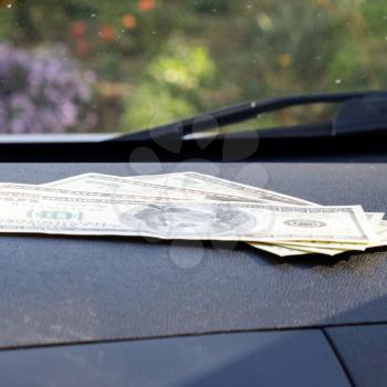 Dollars on a car dashboard under the windshield. American Money.