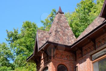Part of the brick building of red brick and shingles on the roof.