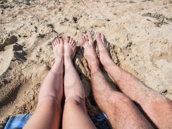Feet of a couple in love on the sea sand on the beach.