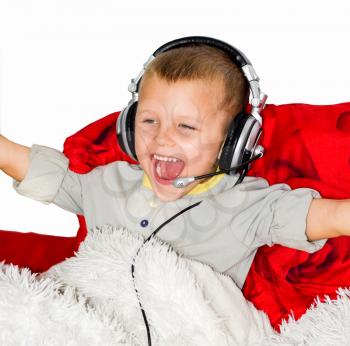 A boy in music headphones with a microphone screams for joy as he arranges the rougs. The boy lies on the bed and listens to music with headphones.