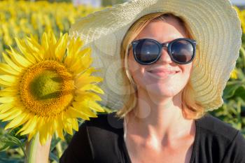 Girl on the field of sunflowers. Girl with sunglasses and a white hat. The sunflower blooms.