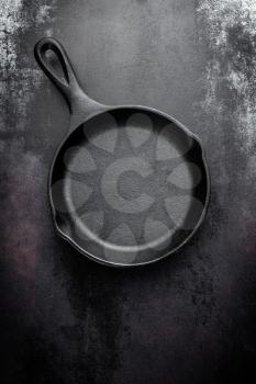 cast iron pan on black metal culinary background, view from above
