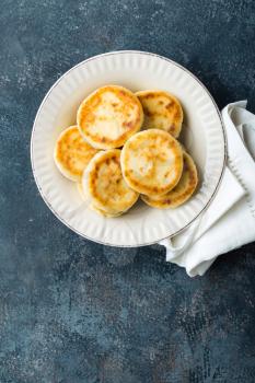 Frying homemade cottage cheese pancakes, syrniki on white plate