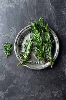 Fresh rosemary twigs on dark culinary background, top view, flat lay, copy space