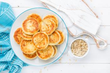 Cottage cheese pancakes with oats, syrniki on white rustic background