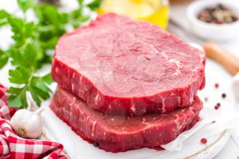 Raw, uncooked beef meat steaks on white wooden background