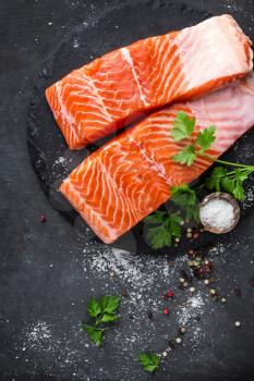 Raw salmon fish fillet on black background