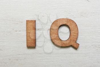 Word IQ (intelligence quotient) are made with wooden letters on an old white wooden background