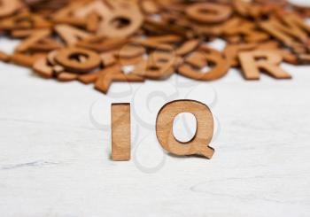 Word  IQ (Intelligence quotient ) made with wooden letters on a background of other blurred letters
